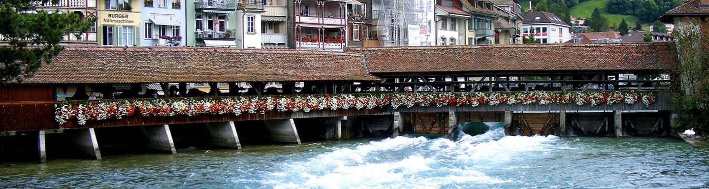 Gedeckte, kunstvoll mit Blumen geschmückte Holzbrücke über die Aare