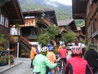 Radlergruppe bestaunt die typischen Holzchalets und deren Blumenschmuck im Dörfchen Brienz